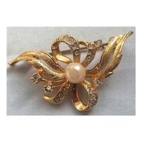 gold coloured brooch with white stones