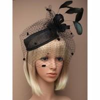 Large black hatinator with spotted net and sinamay loops and feathers on a black elastic